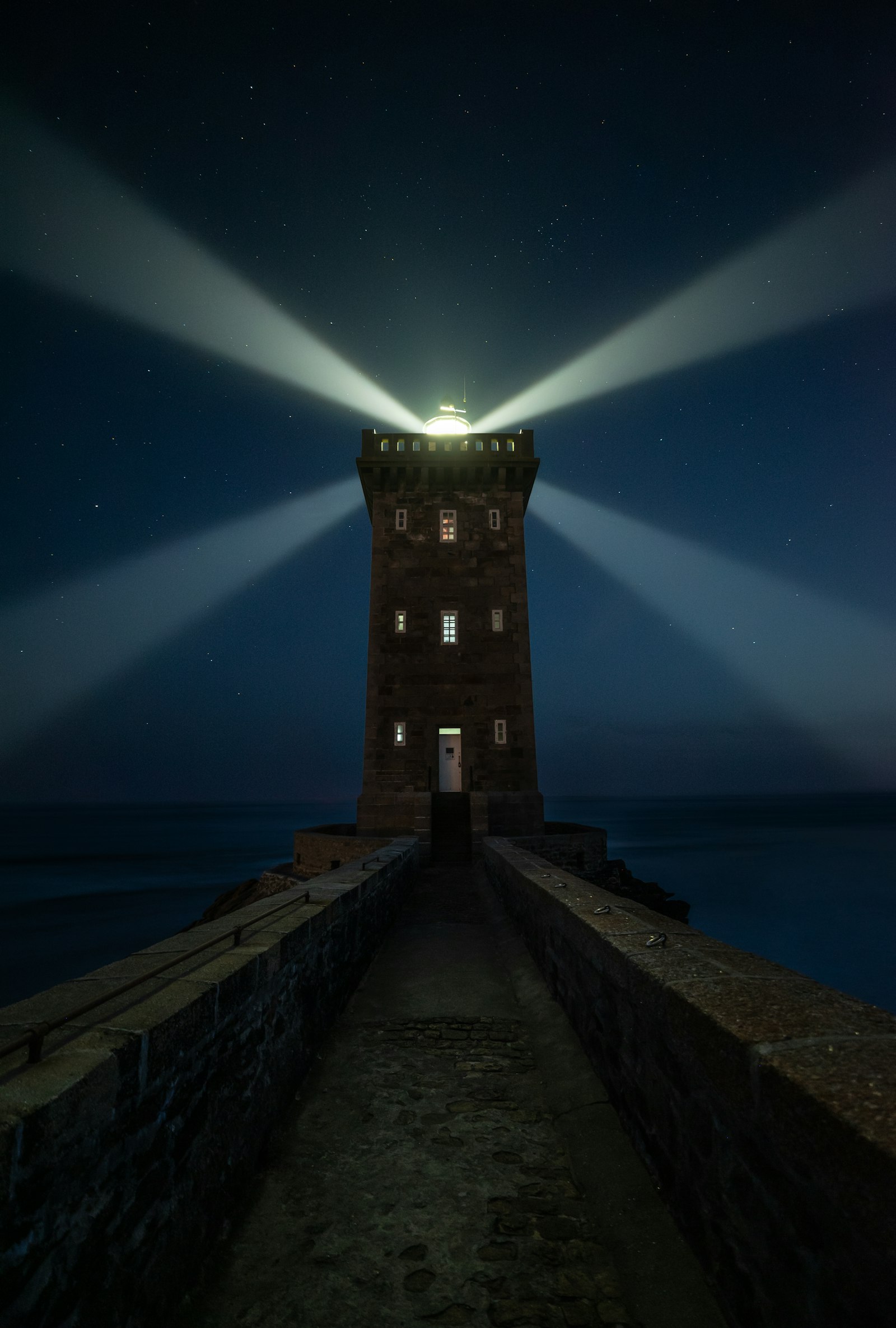 a lighthouse throwing beams into a dark sky